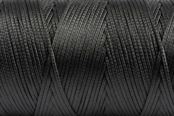 A coil of black thread. Spool of colored threads on a white background. Waxed sewing thread for leather crafts.