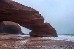 Legzira is a famous coastal arch located in the Sidi Ifni province of Morocco. It is known for its unique rock formations and vibrant orange and red cliffs