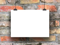 One hanged horizontal paper sheet frame with clips on weathered brick wall background
