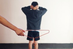 Hand holds cloth hanger to punish a disobey and naughty boy. Concept : Intimidation or stick discipline strategy to control or punish kid behavior that affect to mental in childhood. 