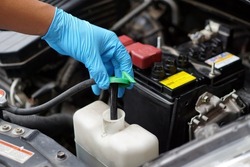 Mechanic's hand is opening bottle of water in car engine to Check auto car's coolant level. Concept : Checking and maintenance car service.                             