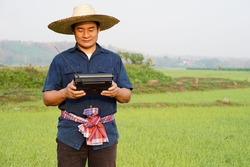 Farmer holds FM-AM radio receiver at paddy field. Concept : Happy working along with music. Country lifestyle. Getting knowledge, information , news , advertisement, songs from listen to radio.       