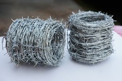 Rolls of barbed wire. Barbed wire is used for make fences , secure property and make border to show the territory of  area.                            