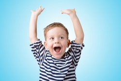 little boy with his hands up smiling on a blue background