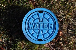 Blue water meter manhole on the grass