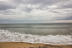 Scenic view of the waves hitting the beach on a cloudy overcast day in the village of Varkala in Kerala, India.