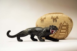 Still life of Mexican crafts. Hand-painted ceramic jaguar and woven palm pot. Crafts isolated on white background.