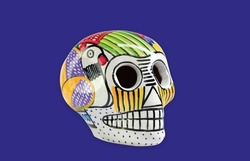 Beautiful and colorful Mexican skull isolated, made of ceramic, and painted by hand. Craft made in Mexico. Purple background. Traditional mexican skull for the Day of the Deads.