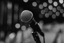Microphone On The Theater Stage Before The Concert With Empty Seats And Blurred Lights On Black And White