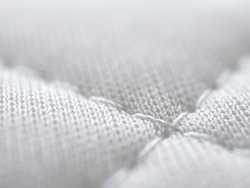 White cloth or fabric background, Macro shot (focus on thread), Detailed of clean mattress textures with copy space, Surface is softness and fluffy, Synthetic fibers and Textiles material.