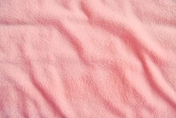 Fluffy gentle pastel pink fabric with waves and folds. Soft pastel textile texture. Abstract background.