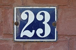 A blue house number plaque, showing the number twenty three (23) 