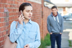 Woman Calling For Help On Mobile Phone Whilst Being Stalked On City Street By Man