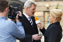 Female Journalist With Microphone Interviewing Businessman 