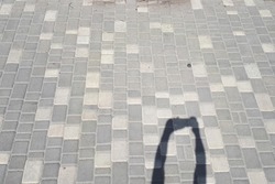 Shadow of human hands with phone on a city tile. Copy space, photo with minimalism