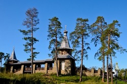 Beautiful wooden chapel of All Saints of Valaam. Chapel of the Apostles Peter and Paul. Horizontal photo of a chapel in a green forest against blue sky