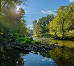 landscape river with trees on the sides against the sun