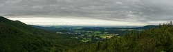 panorama view from hill in valley with small town in forests