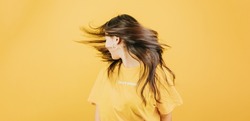 Young african woman waving hair and dancing happy and cool attitude concept posing isolated over yellow color wall background. Daily expressions with copy space in studio.