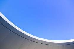 The curved wall contrasts with the sky. Abstract architecture contrasting with the blue sky With clear and beautiful light shadows Modern concepts. Background image for design.