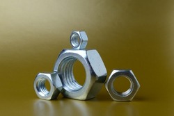 composition of new nuts and bolts of different sizes on a yellow background