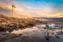 Golden lighthouse captured by a professional photographer at sunset on a coastline