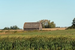 A weathered old barn, abandoned in a field of an old farm yard in rural Saskatchewan in the Canadian prairies.
