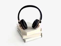 Isolated headphones standing on books for Podcast and audio book concept. The objects are on white background.