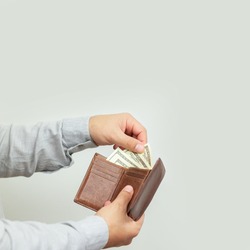 Man holding open leather wallet full of money or paper dollar bills