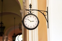 Old fashioned analog clock hanging on building wall outdoors