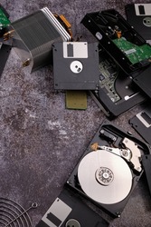 Composition of various computer components on a dark background similar to cement, different computer components such as hard drives, disk drives, graphic controller, micro chips, fans and heat sinks.