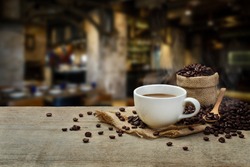 Hot Coffee cup and coffee beans roating on the wooden table and the coffee shop background with copy space