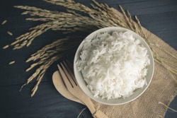 Cooked rice with dry ears of jasmine rice and wooden table