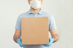 Delivery man holding cardboard boxes in medical rubber gloves and mask. copy space. Fast and free Delivery transport . Online shopping and Express delivery . Quarantine 