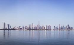 Dubai Downtown skyline panorama with reflections in Dubai Creek, cold colors, seen from Dubai Creek Harbour promenade.