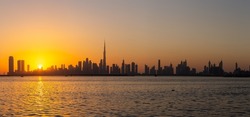 Dubai Downtown skyline panorama during sunset seen from Dubai Creek Harbour promenade.