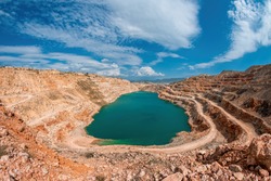Emerald green lake in flooded opencast mine, open pit. Oval lake in mining industrial crater, acid mine drainage in rock. Open pit mine with lake. Quarry fluxes for the metal industry.