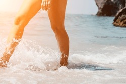Sea beach travel - woman walking on sand beach leaving footprints in the white sand. Female legs walking along the seaside barefoot, close-up of the tanned legs of a girl coming out of the water.