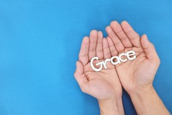 Hands praying for grace from God in blue background top view. 