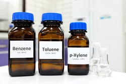 Selective focus of benzene, toluene and xylene liquid chemical compound in glass amber bottle inside a chemistry laboratory with copy space. BTX aromatic hydrocarbons used in petrochemical industry.