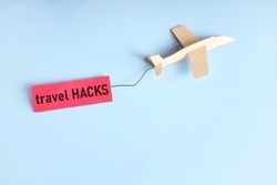 Travel hacks and tips concept. Wooden airplane flying with red tag.