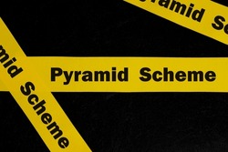 Pyramid scheme alert, caution and warning concept. Yellow barricade tape with word scam in dark black background.
