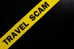 Travel scam alert, caution and warning concept. Yellow barricade tape with word in dark black background.