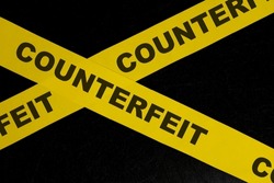 Counterfeit product and item caution and warning concept. Yellow barricade tape with word in dark black background.