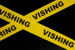 Vishing scam alert, caution and warning concept. Yellow barricade tape with word vishing in dark black background.