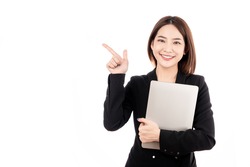 Asian businesswoman with black suit holding a laptop and pointing to present copy space with big smile beaming face in white isolated background.