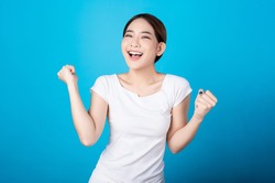 Beautiful young asian woman pretending to be happy with big smile happy beaming face in seamless blue  isolated background. Presenter promotion, happy lifestyle, fresh pretty girl concept.