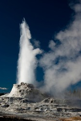 Castle Geyser erupts, sending a colum of steam skyward in Yellowstone National Park.