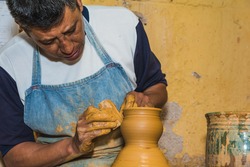 Mexican potter craftsman, working the clay with his hands in his workshop to create sculptures, vases, jugs, vases etc, using traditional methods.