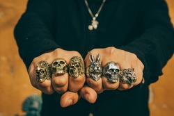 Young man wears rough and masculine rings of different figures such as animals and skulls.